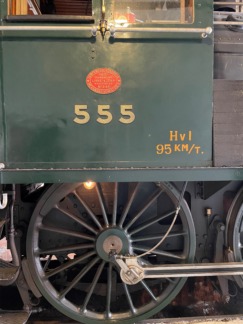 Närbild av sida på ånglok där enbart ett drivhjul syns. Ovanför numret 555 i gult, bottenfärg vagnsgrön